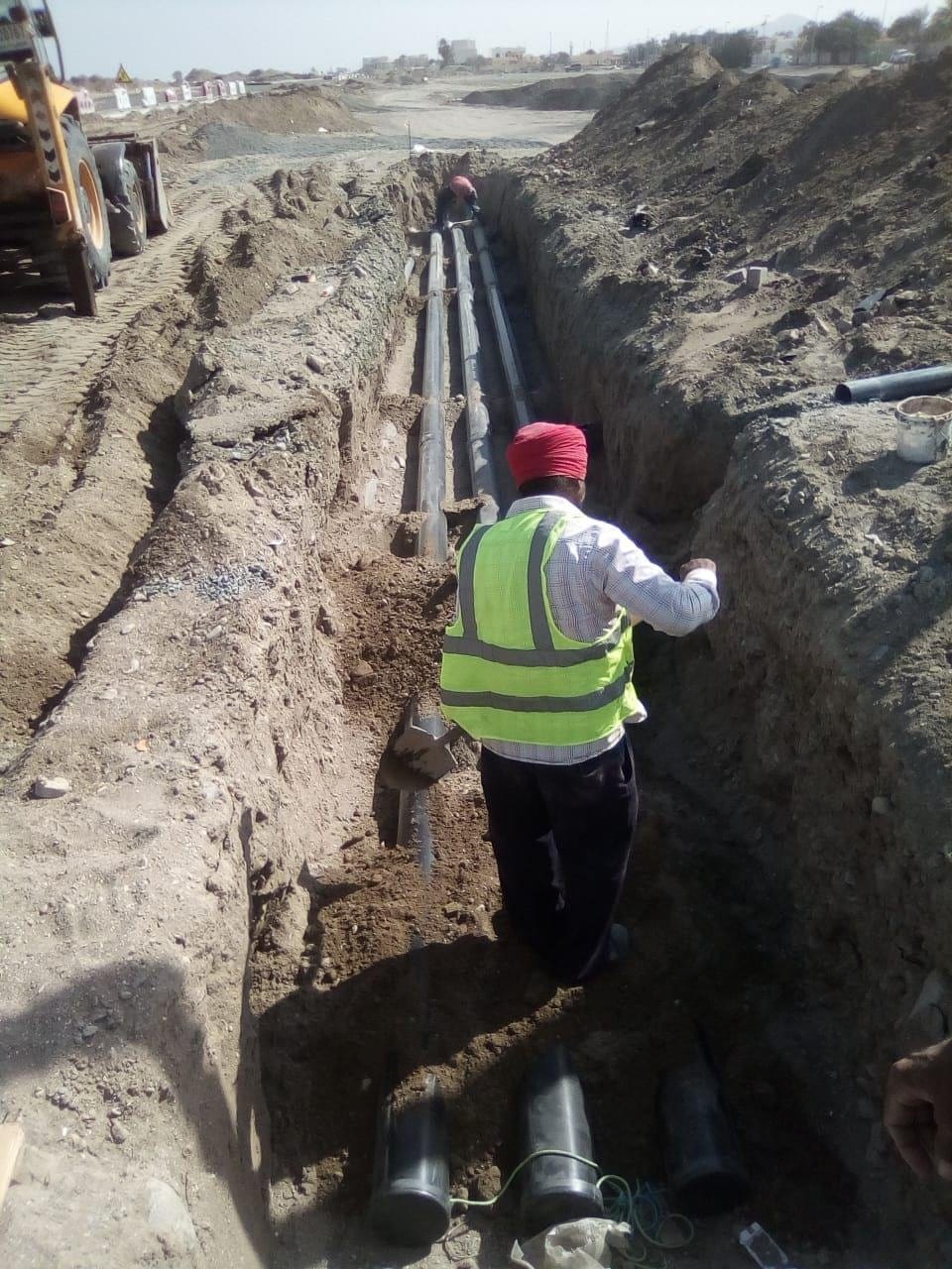 Crew laying cables in an excavated trench