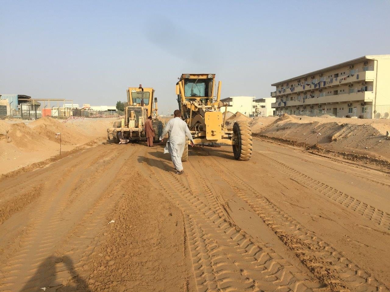 Motor grader forming a road corridor beside a residential block