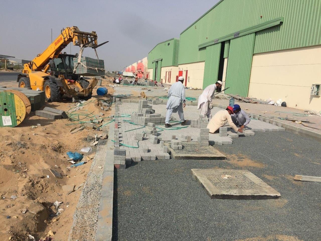 Telehandler delivering interlock pallets to a paving crew