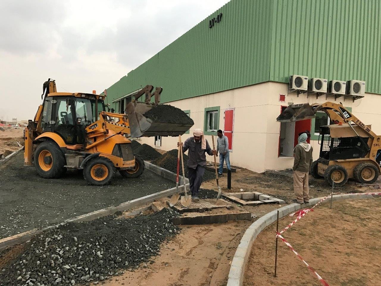 Backhoe loader and crew laying kerbs