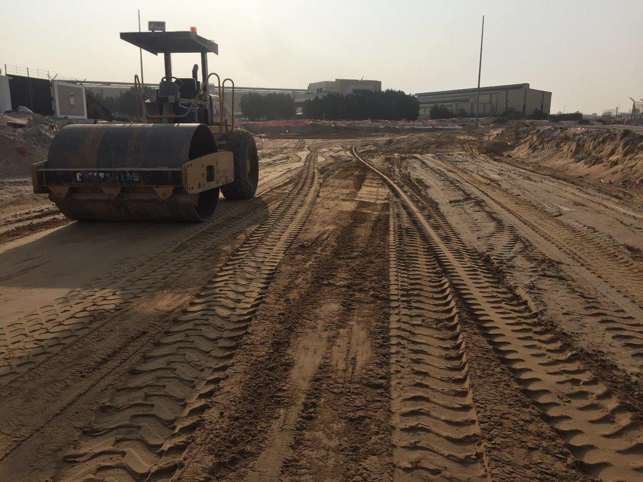 Vibratory roller compacting subgrade with buildings behind