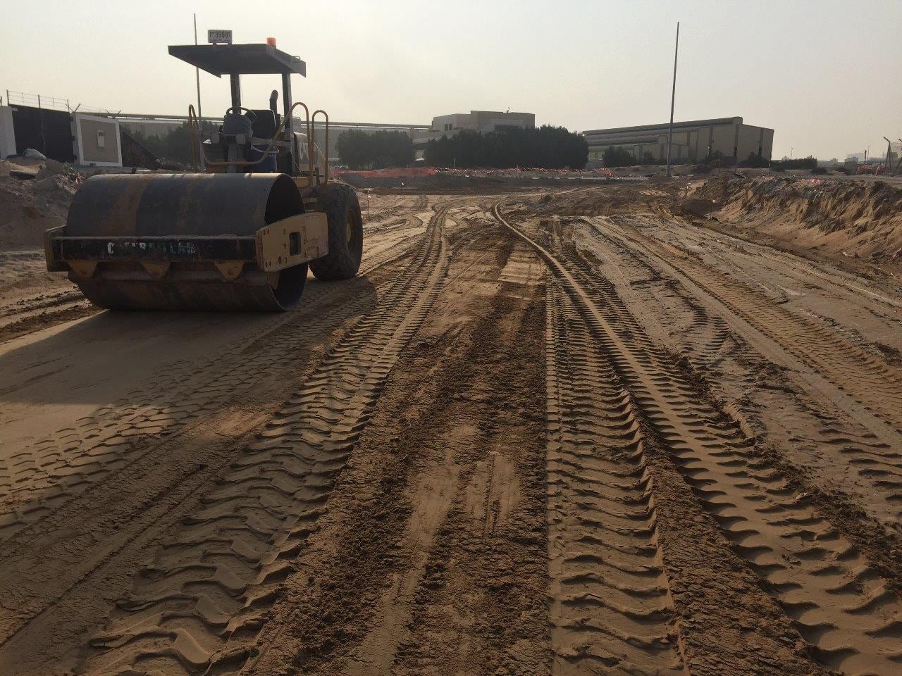 Vibratory roller compacting subgrade with buildings behind